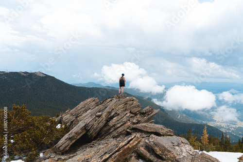 Fototapeta Naklejka Na Ścianę i Meble -  A lone figure stands on the top of a mountain on a cloudy day