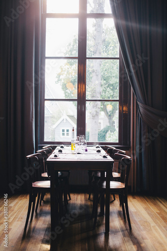 Empty dinner table with a big window at the end with light falling in