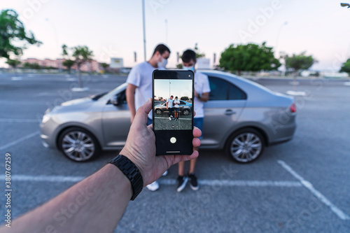 Dos amigos con smartphone delante de un coche