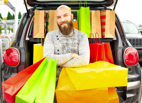 Smiling man having fun with lots of bags on a shopping day for the black friday. Concept about how fun is to buy things on these promotional days and get ready to celerate the festivities with friends photo