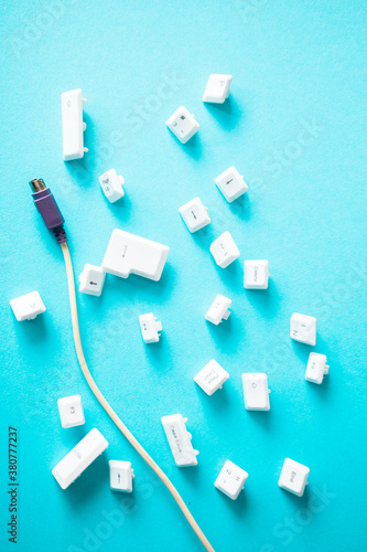 Separated pc keyboard buttons with input cabel on blue background photo