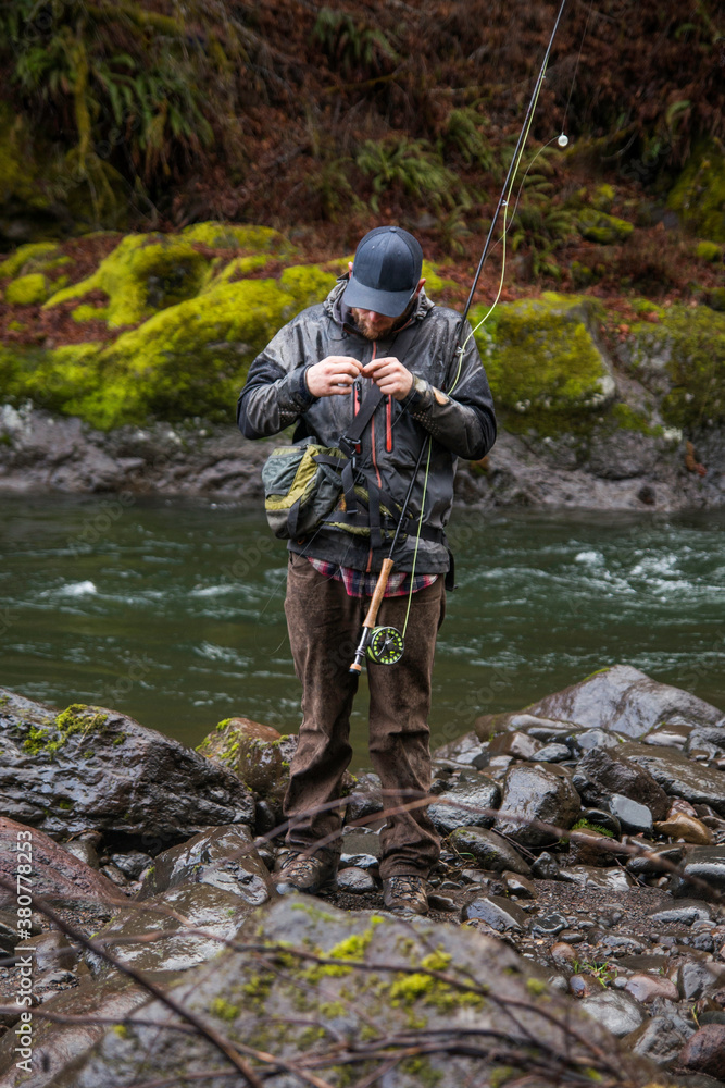 A fly fisherman adjusting his line on the bank of a river A fly fisherman adjusting his line on the bank of a river