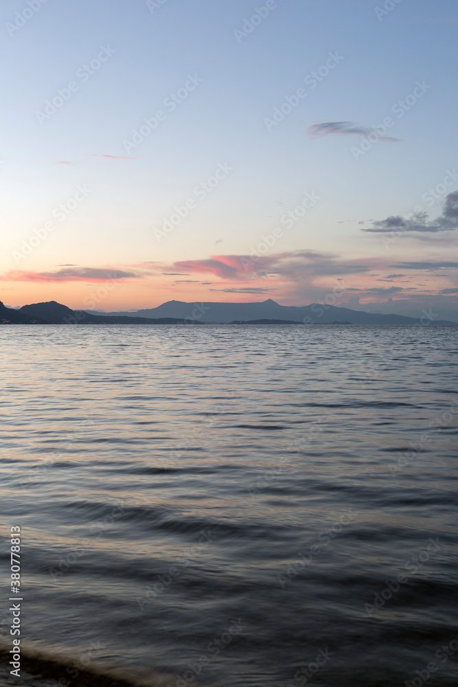 Looking across the sea of a curved island from shore to shore after sunset Looking across the sea of a curved island from shore to shore after sunset