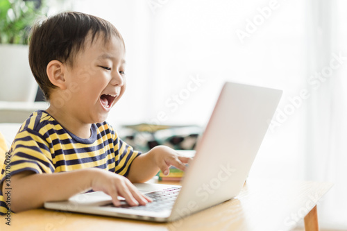 Asian toddler boy student study online learning online education video call zoom teacher.Happy boy learn english online with laptop at home.New normal.Covid-19 coronavirus.Social distancing.stay home.