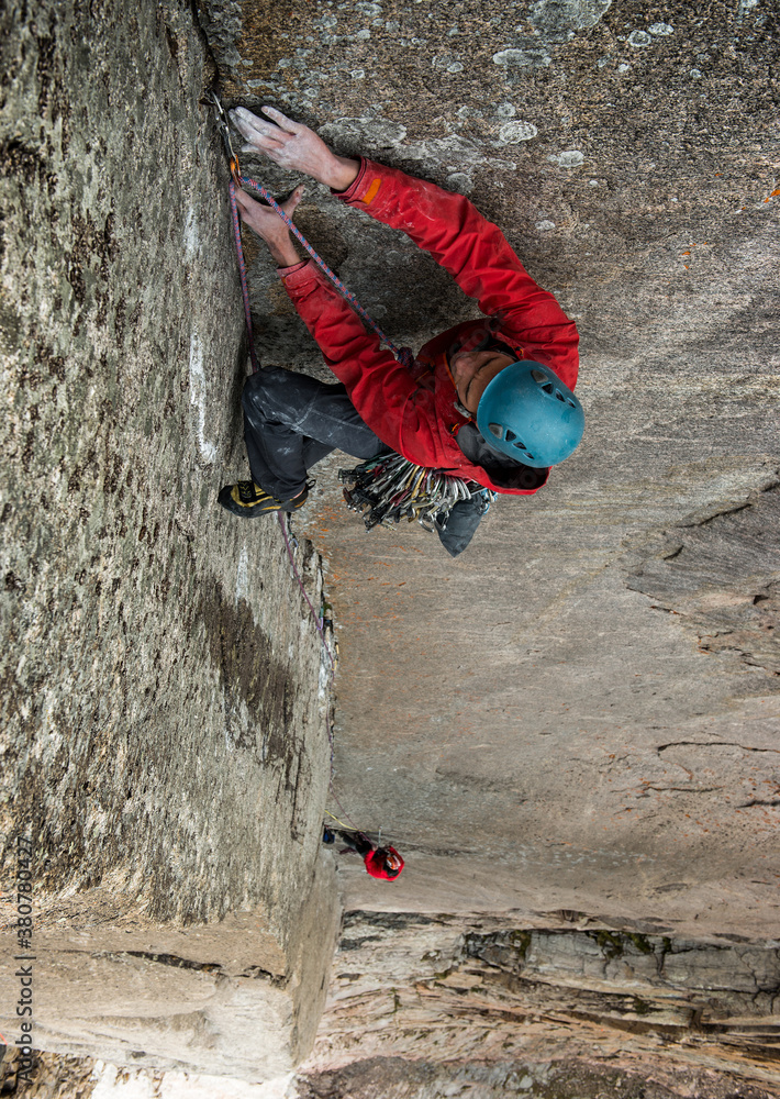 Rock climber reaching for difficult hold on steep alpine climb