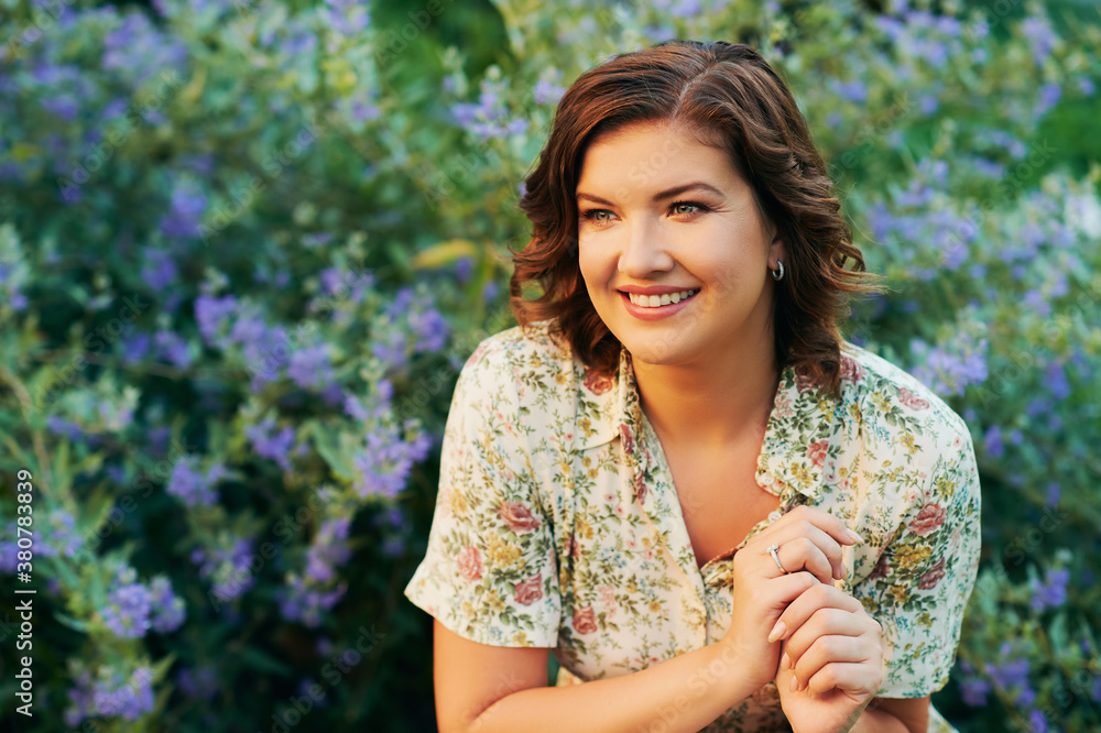 Sunny portrait of happy young woman posing in beautiful garden with purple flowers Sunny portrait of happy young woman posing in beautiful garden with purple flowers