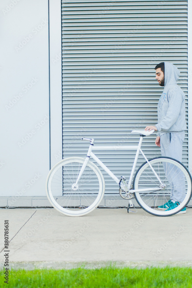 Modern young man with his bike in front of minimalsitic architecture background.
