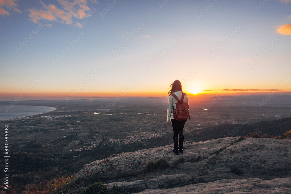 Hiker woman standing on the top of a mountain at sunset. Hiker woman standing on the top of a mountain at sunset.