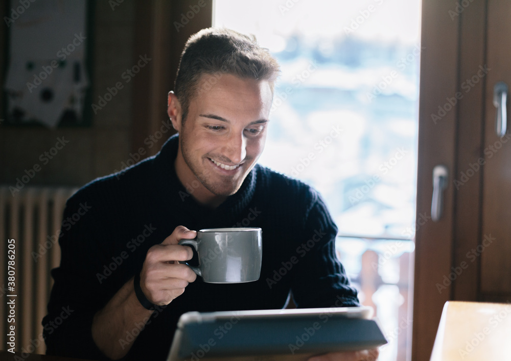 Young man is using the tablet in the kitchen Young man is using the tablet in the kitchen