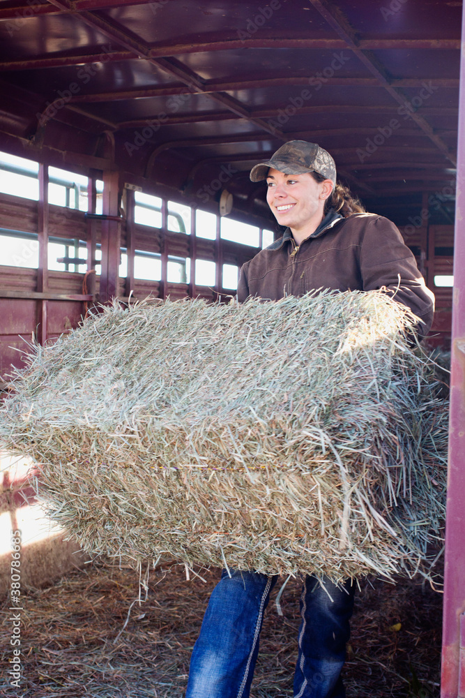 country girl carrying hay bale out of trailer country girl carrying hay bale out of trailer