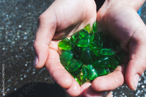 Womans hands hold up a collection of green sea glass photo