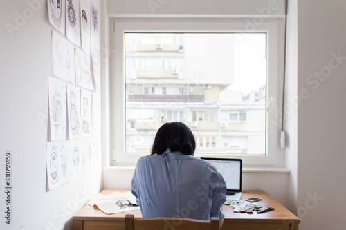 Back view of freelance designer working at home on computer photo