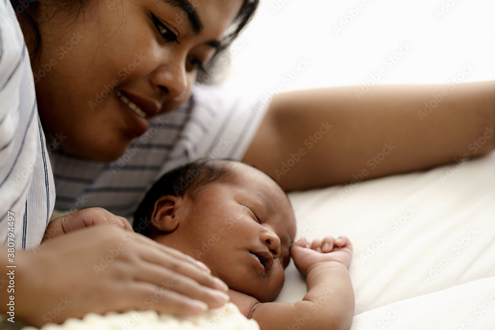 african american infant baby lying on bed with mother watching beside african american infant baby lying on bed with mother watching beside