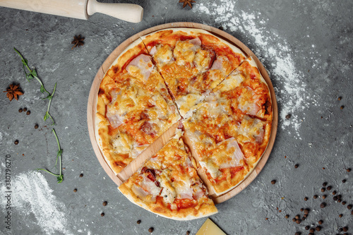 pizza with cheese, sauce and ham, bacon, salami on a gray dark background
