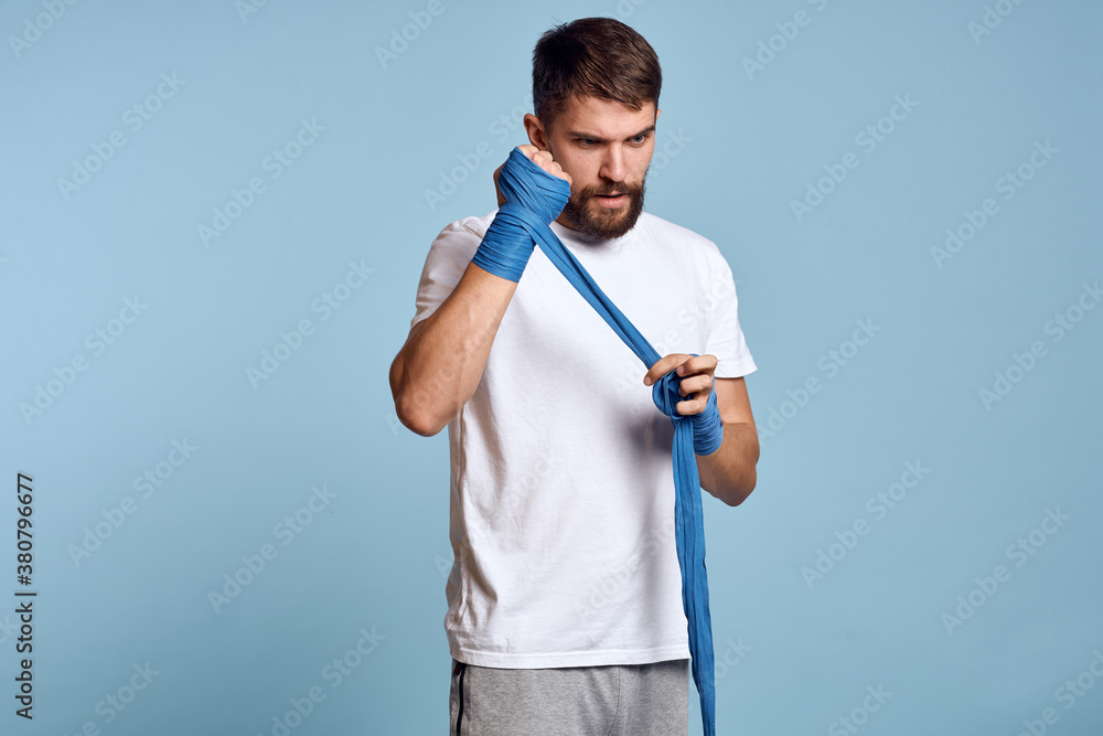 sport man in white t-shirt boxing bandages on hands blue isolated background exercise workout sport man in white t-shirt boxing bandages on hands blue isolated background exercise workout