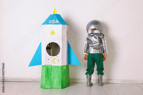 Back view of young boy wearing handmade astronaut uniform next to a diy rocket. photo