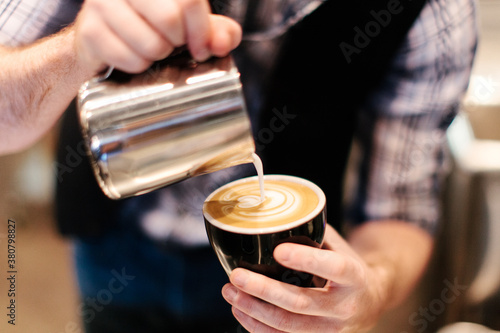 Barista pouring foam / froth art in a coffee cup photo