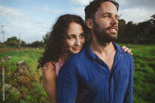 Young, romantic couple standing together outside smiling and cuddling in nature photo