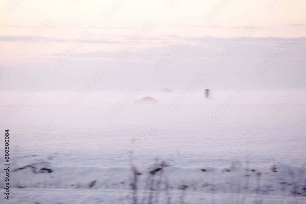 Car driving though dense fog at sunset on a cold winter day Car driving though dense fog at sunset on a cold winter day