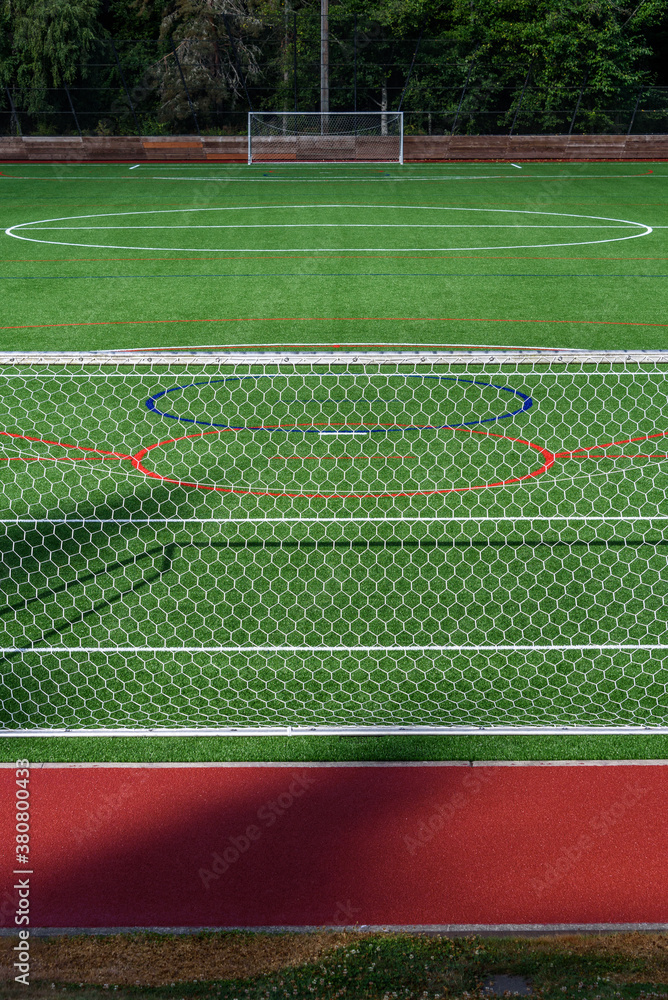 Fototapeta premium Newly installed artificial turf sports field on a sunny day, soccer goals 