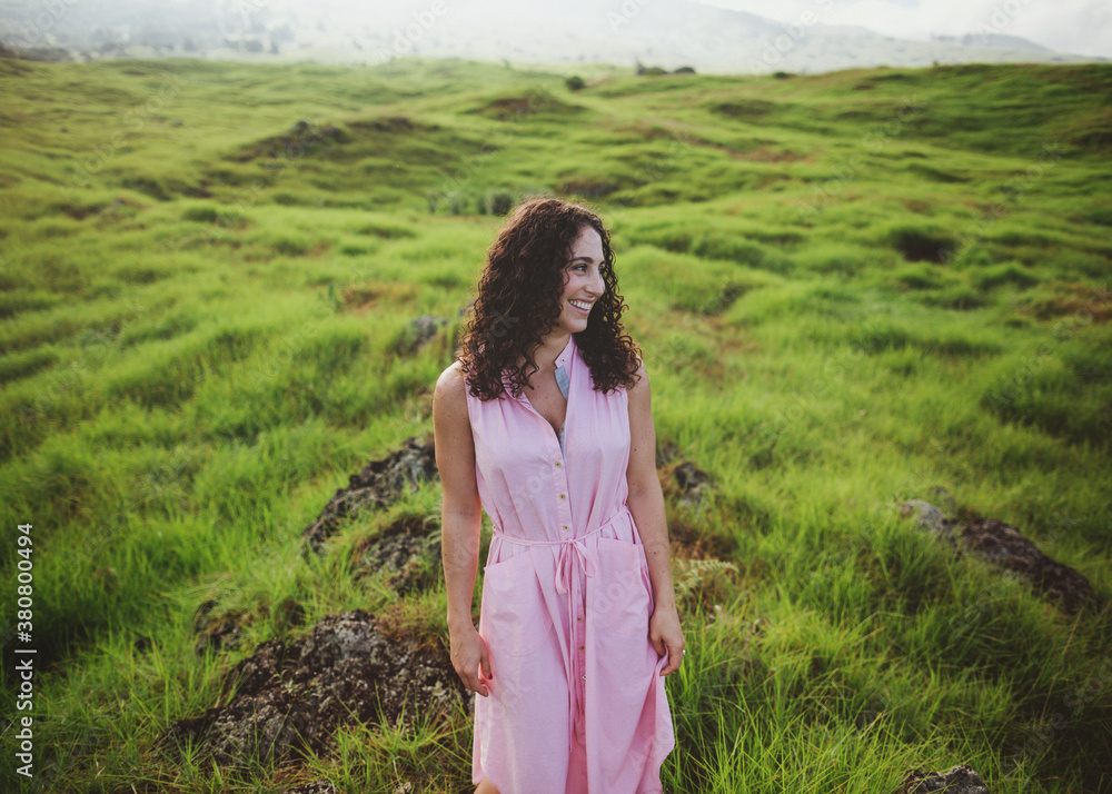 Beautiful woman with curly brown hair smiling outside in nature - candid Beautiful woman with curly brown hair smiling outside in nature - candid
