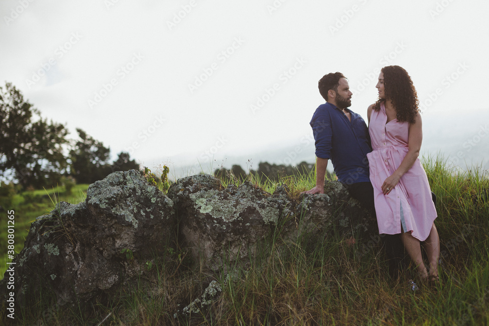 Young, romantic couple standing together outside smiling and cuddling in nature Young, romantic couple standing together outside smiling and cuddling in nature