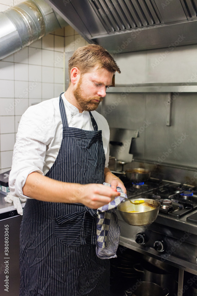 A chef or cook preparing and stirring in a bowl while standing in front of the stove A chef or cook preparing and stirring in a bowl while standing in front of the stove