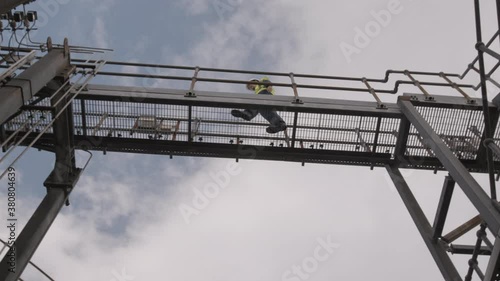 Wallpaper Mural Industrial worker walking on walkway bridge on industrial site wearing protective workwear Torontodigital.ca