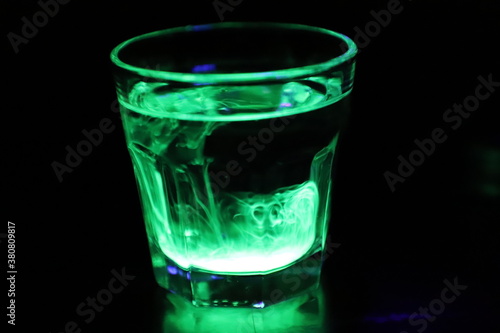 A Glass with a Glowing Green and Yellow Liquid Swirling Around Inside