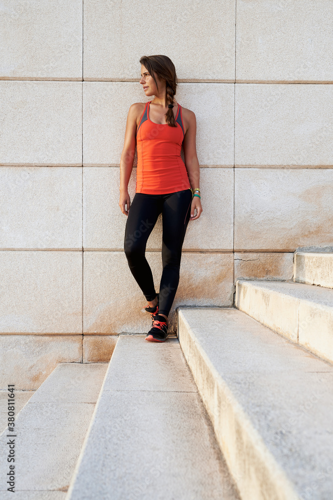 Young sportswoman in yoga pants and top posing on stone wall Young sportswoman in yoga pants and top posing on stone wall