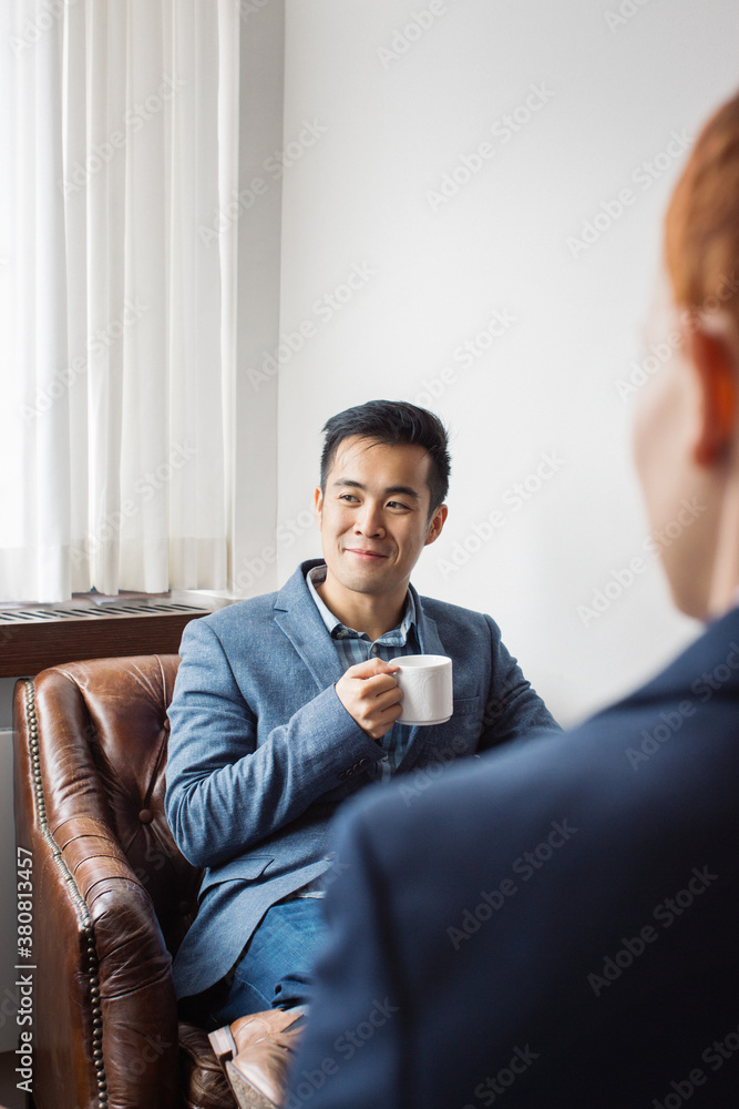 Indoor Portrait of Young Smiling Asian Man Sitting in Leather Chair Indoor Portrait of Young Smiling Asian Man Sitting in Leather Chair