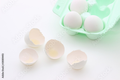 Broken white eggshell and tray with eggs