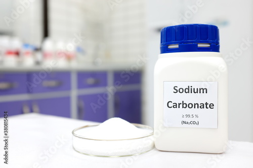 Fotomural Selective focus of a bottle of sodium carbonate chemical compound or soda ash beside a petri dish with solid crystalline powder substance