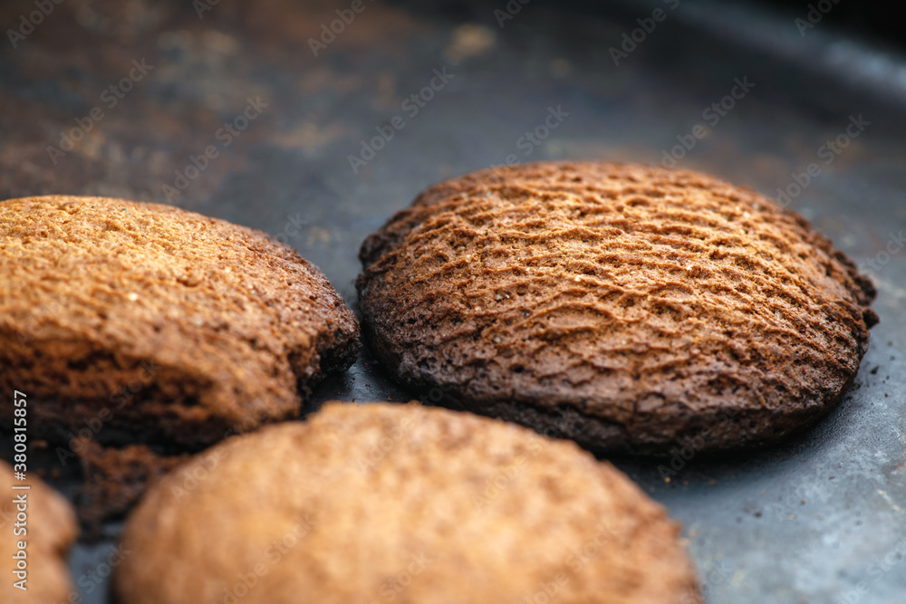 Burnt cookies. Burnt, burnt oatmeal cookies lie on a black baking sheet. Vertical photo Burnt cookies. Burnt, burnt oatmeal cookies lie on a black baking sheet. Vertical photo