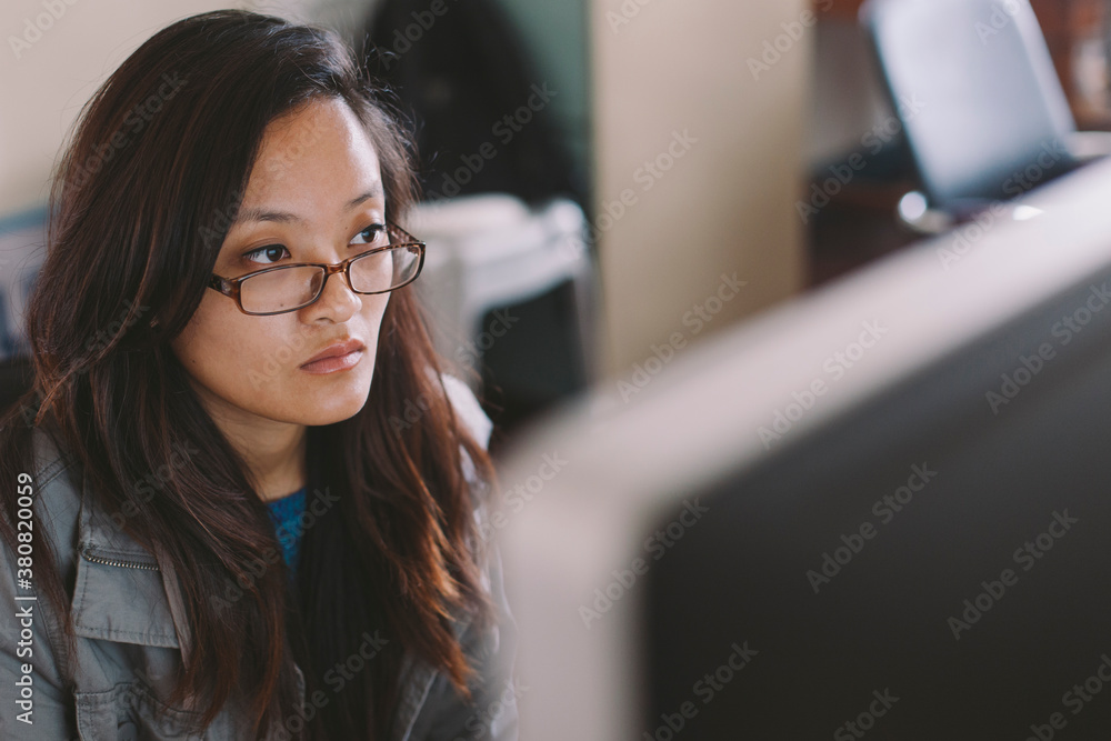 A young asian woman working on a computer. A young asian woman working on a computer.