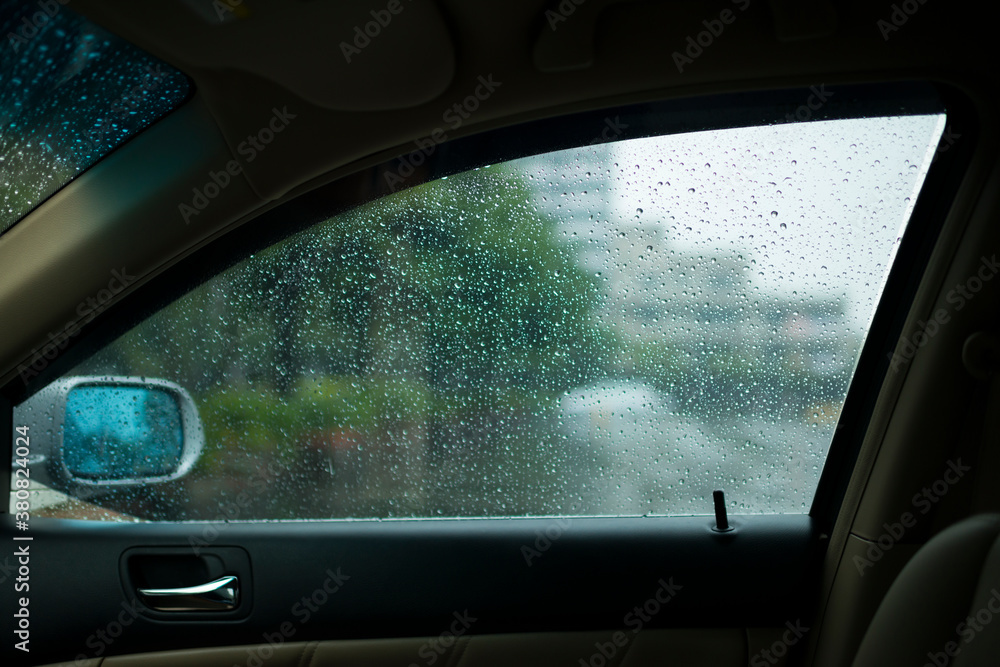 Raindrops beading on glass of car window on wet misty day, view from inside the car Raindrops beading on glass of car window on wet misty day, view from inside the car