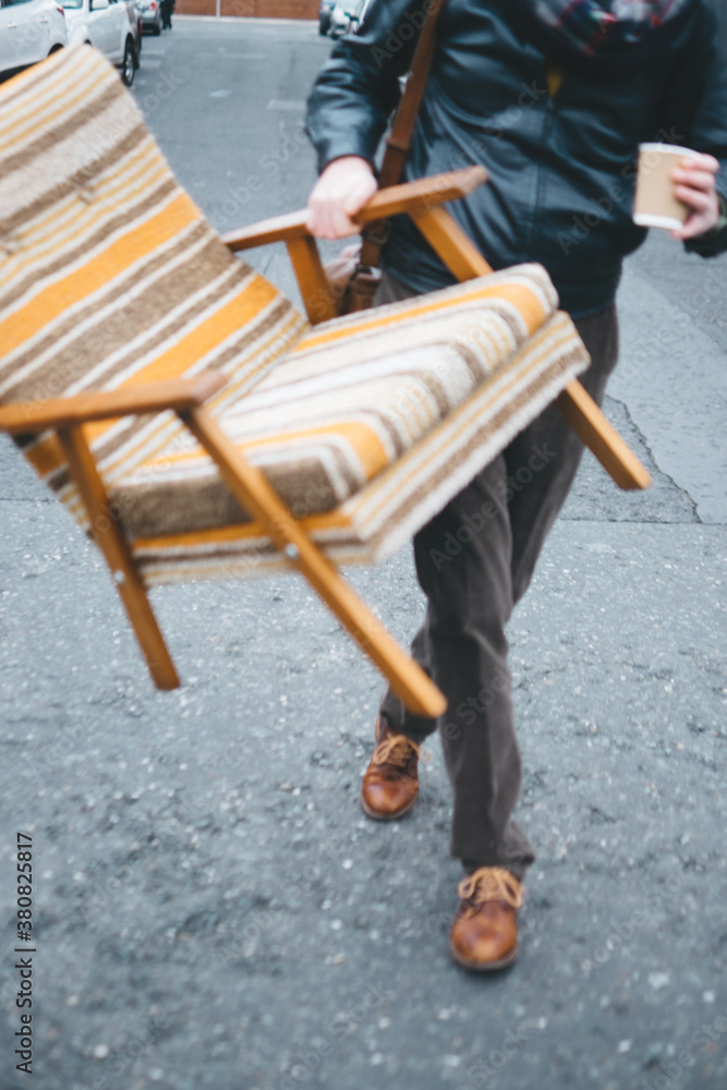Stylish Man Carrying an Armchair on the Street Stylish Man Carrying an Armchair on the Street