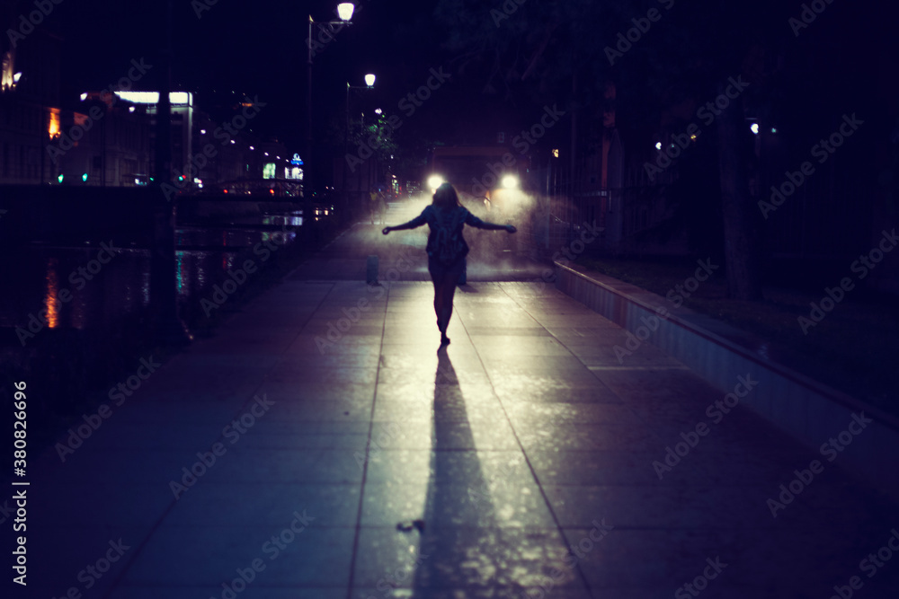 Young woman standing in the night in front of a vehicle lights Young woman standing in the night in front of a vehicle lights