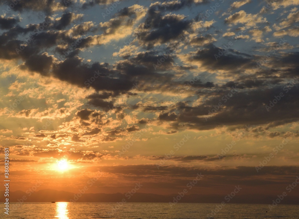 Rising sun in cirrus clouds on the sea coast.