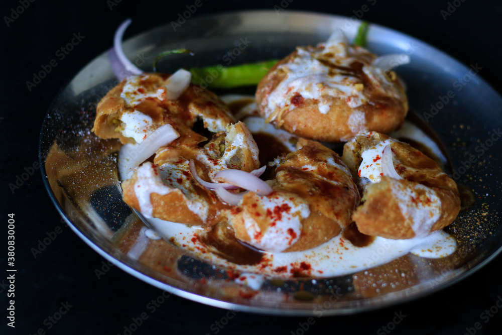 Indian chat kachori topped with curd and onions and laid on a black background Indian chat kachori topped with curd and onions and laid on a black background