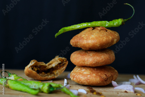 Canvas Print Indian snack kachori served with green chilli and onions in a black background