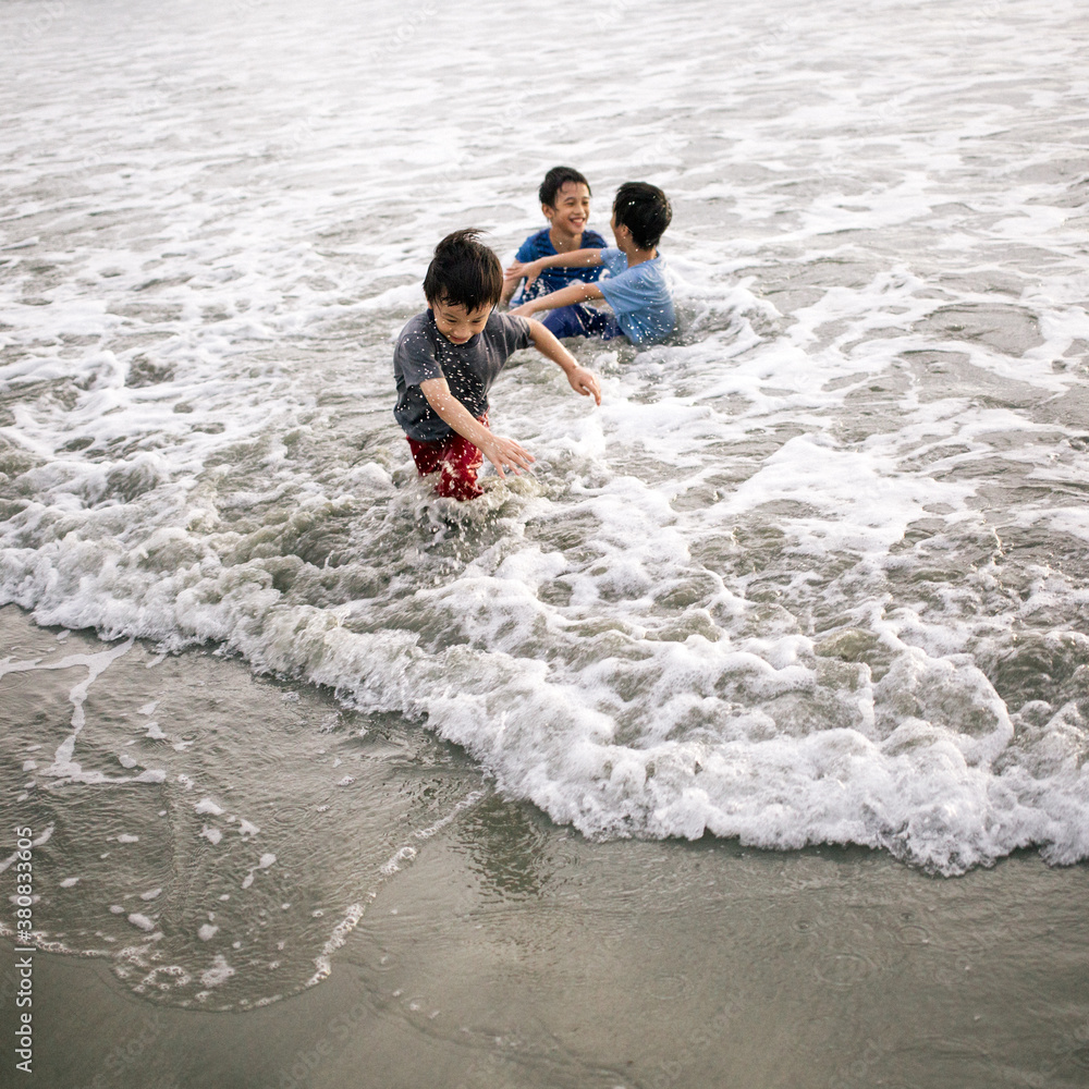 Three brothers enjoying themselves fully playing in the beach. Three brothers enjoying themselves fully playing in the beach.