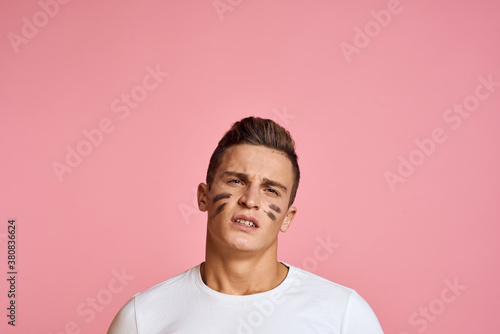 Energetic man with a bat on a pink background T-shirt face make-up black lines aggression model