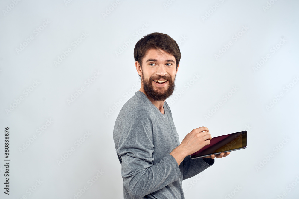 A bearded man with a tablet in his hands a gray jacket technology internet light background A bearded man with a tablet in his hands a gray jacket technology internet light background