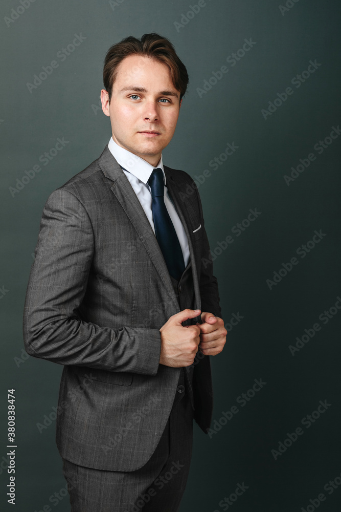 Portrait of a businessman who holds his suit with his hands and looks at the camera. Light background Portrait of a businessman who holds his suit with his hands and looks at the camera. Light background