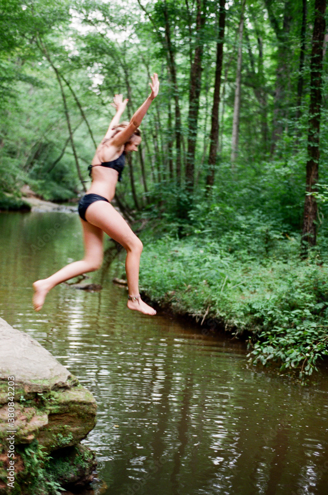 Teen jumping off of rocks into river Teen jumping off of rocks into river
