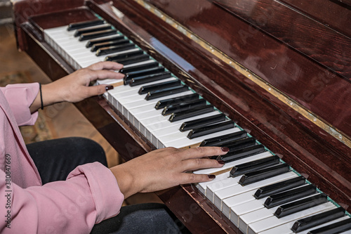 Close-up of the hands of a girl playing the piano. Teenage girl learns to play the piano.