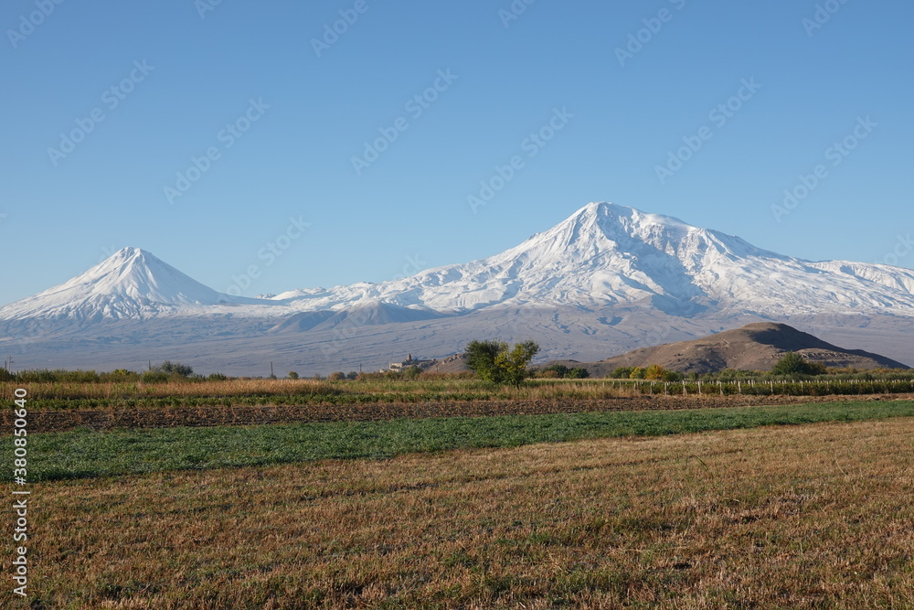 Ancient Armenian monastery Khor Virap against the background of the snow-capped peak of Ararat and fields
