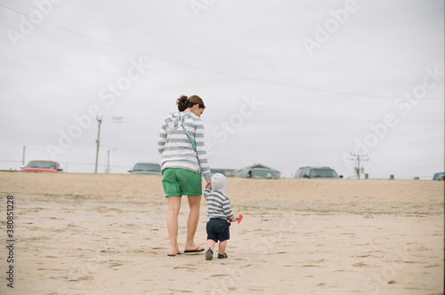 Mother and son holding hands walking home from playing on the beach photo