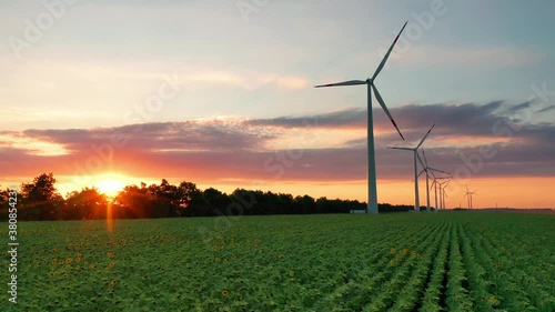 Aerial view of wind turbines standing in sunset. Aerial View of a Farm With Wind Turbines. Generating Clean Renewable Energy. bright orange sunset wind park drone. Alternative energy 